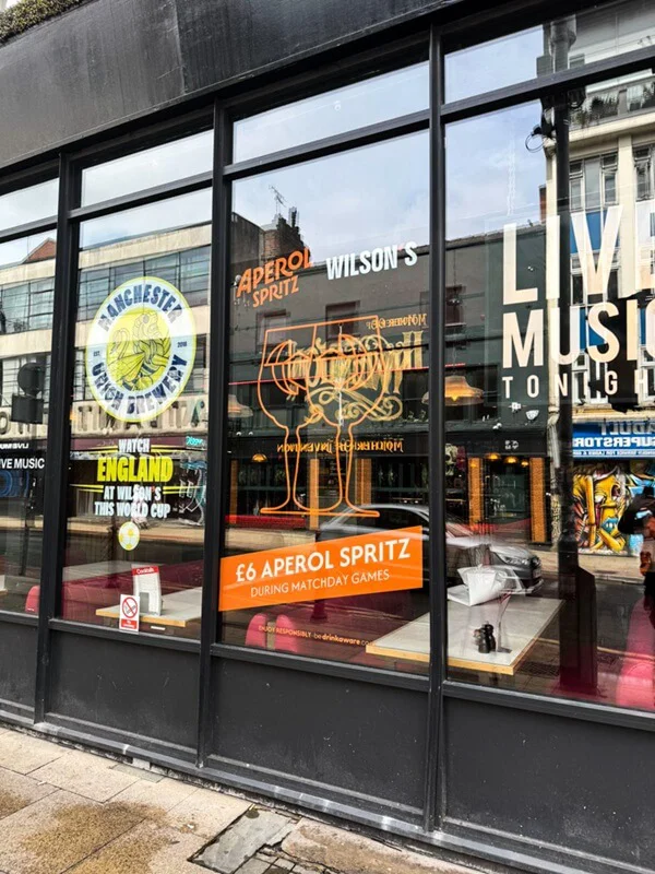 An image of a restaurant's storefront window graphics and signage showing food and live music.